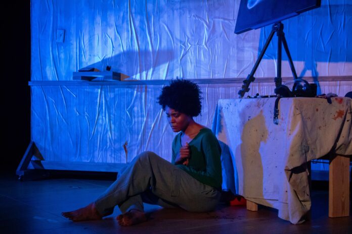 Ang(ela) Bey sits on the ground, distraught in a scene from COMET.