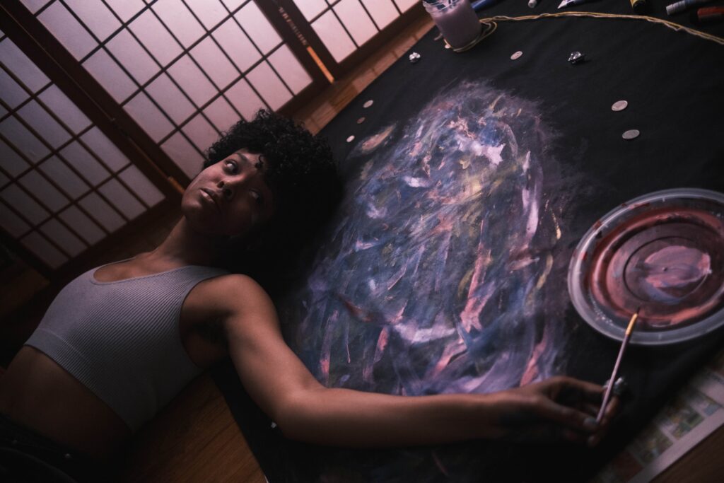 Artist Ang(ela) Bey lays down on painting
