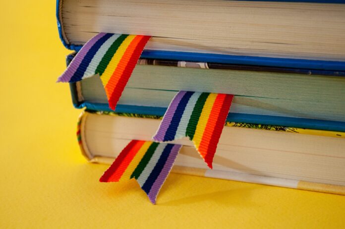 a stack of three books with rainbow ribbon bookmarks is on the table. Concept back to school, freedom, independence