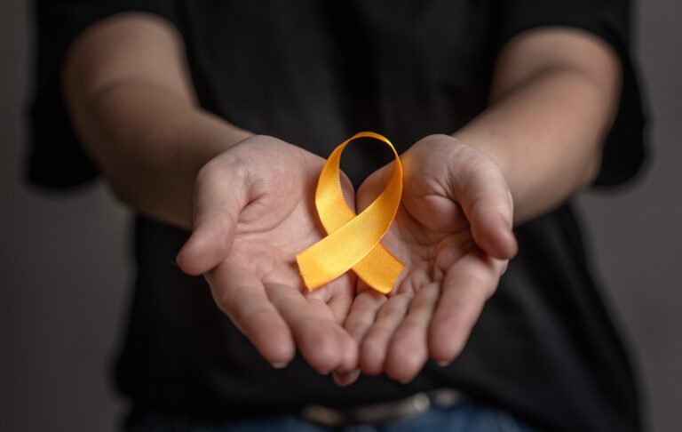 Hands hold yellow ribbon. Concept of suicide problems and their prevention.