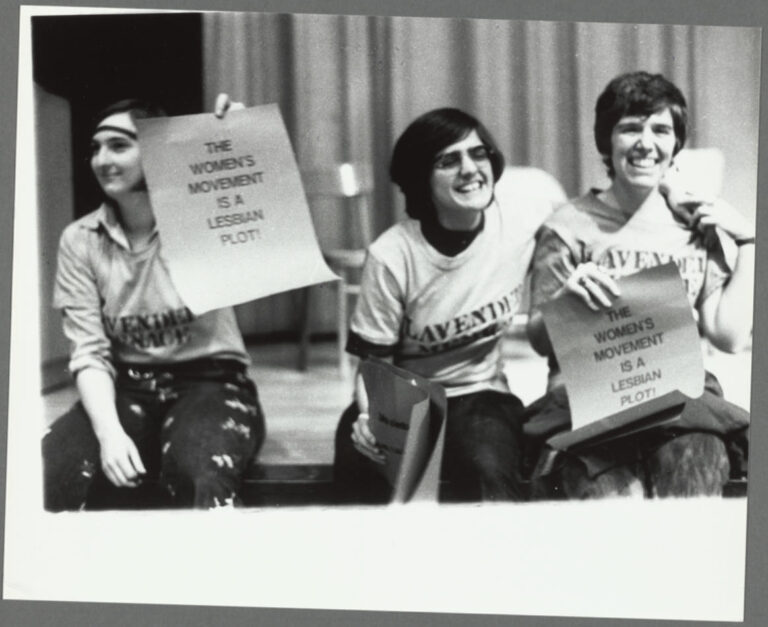 From left, Lita Lepie, Judy Cartisano and Arlene Kisner storm the stage holding signs that say 