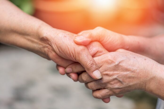 Aging society concept. Hands of old adults holding support each other in nursing home