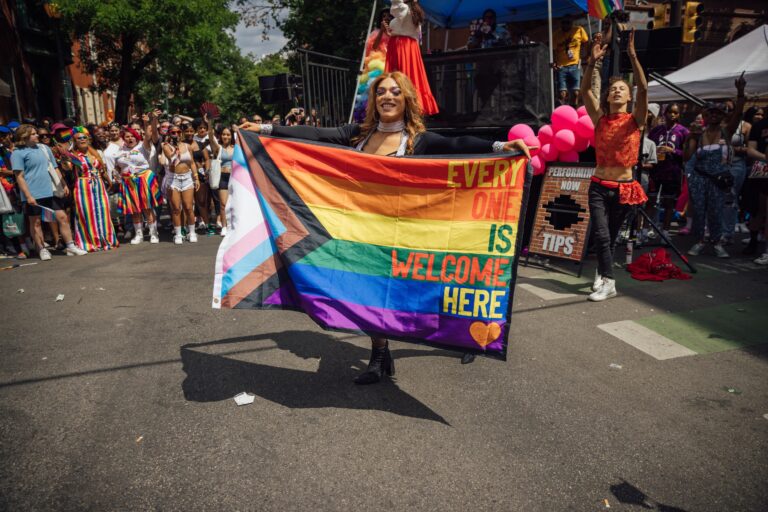 Stephanie Ramones holds a Progress Pride flag that reads, 