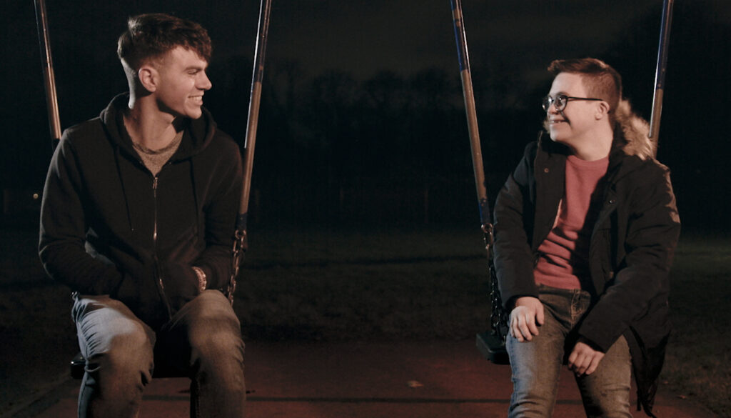 Sam Retford and George Webster in a scene from ‘S.A.M.’ The two are sitting on a swing set while looking at each other.