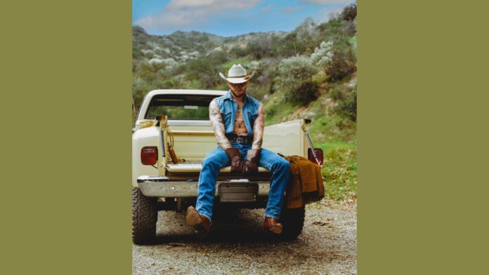 Orville Peck sits on the back of a truck.