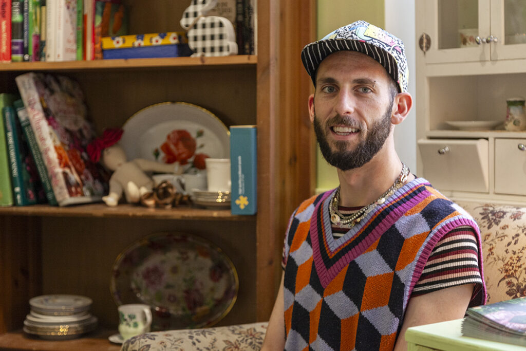 Judson Browning sits in front of a shelf with various trinkets sitting on it.