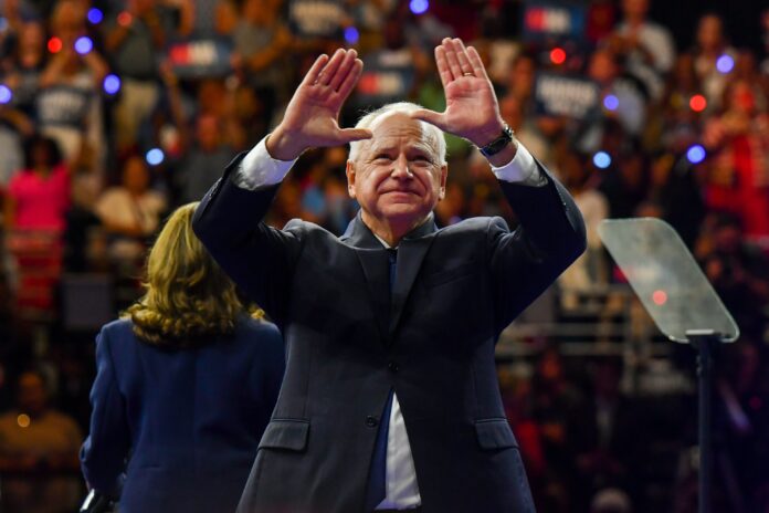 Tim Walz holds up his hands during a rally in Philadelphia