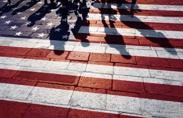 Shadows of group of people walking through the streets with painted Usa flag on the floor. Concept political relations with neighbors.