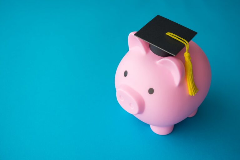 Pink piggy bank and mortarboard on blue background with copy space. Money savings and financial planning for education in university, college or international abroad study concept.