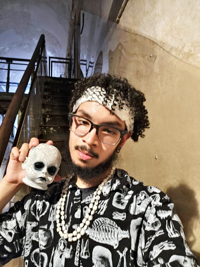 Anthony Salas wears a skeleton-themed t-shirt while holding a doll head.