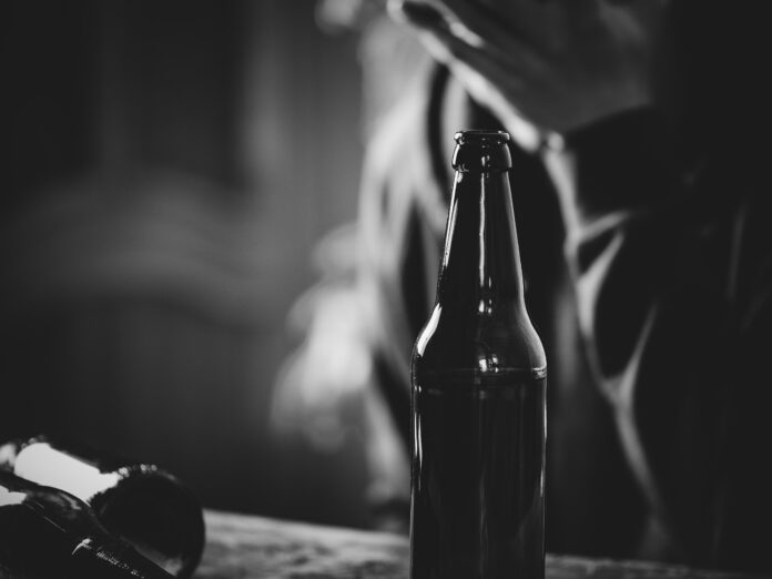 A man holding a bottle of beer in his hand. The concept of alcoholism and problems in life