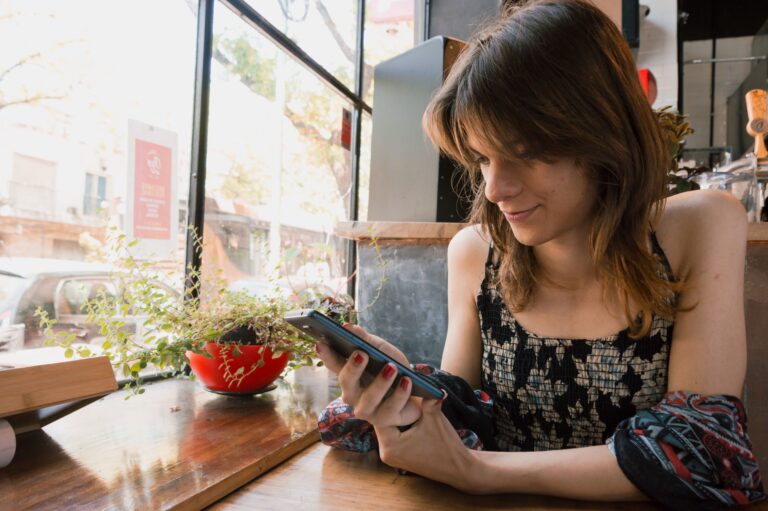 Woman alone, sitting using the phone sitting in a restaurant, browsing the internet, using applications and social networks.