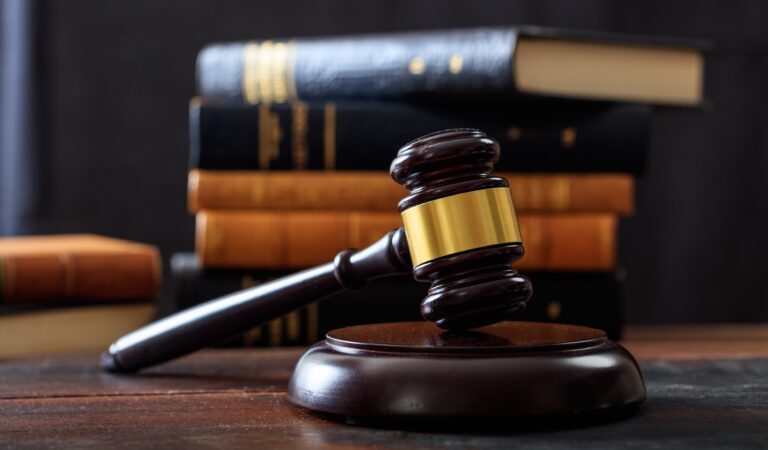 Law gavel on a wooden desk, law books background